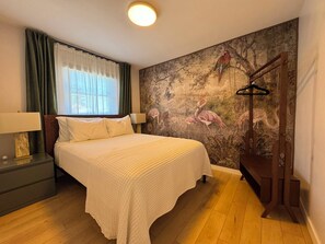 Una camera da letto con un letto, un comodino, una lampada, un armadio e un affresco sulla parete.