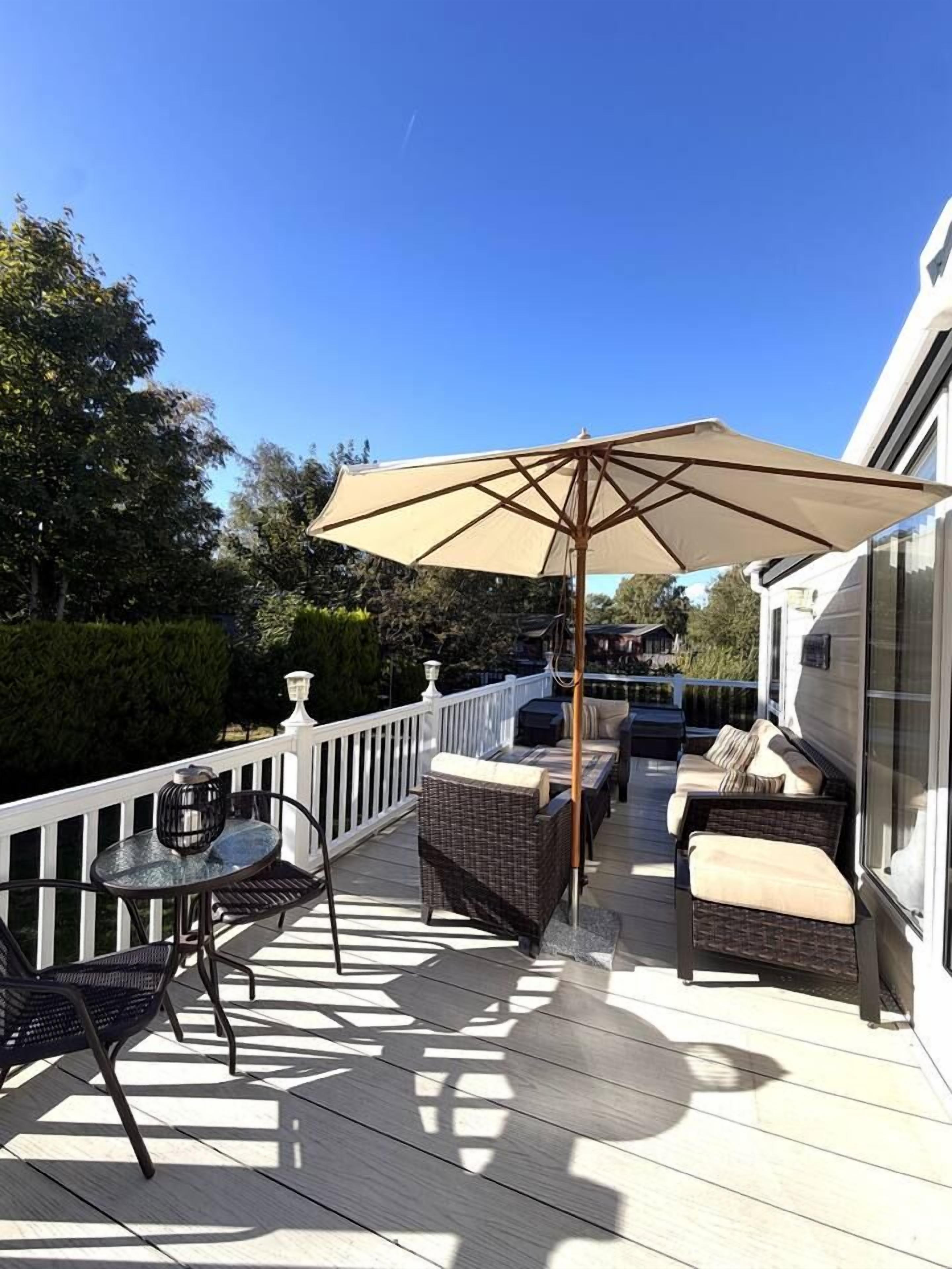 A deck with outdoor furniture, including a table and chairs, and a large umbrella providing shade.