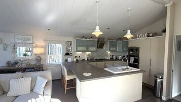 Una cocina moderna con una isla central, iluminación colgante y un comedor con sofá y sillas.
