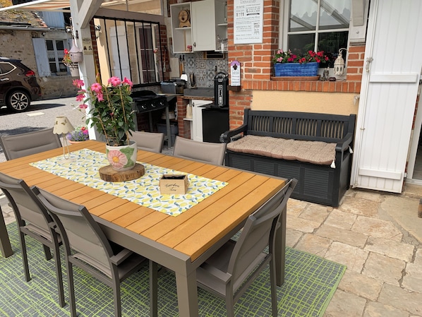 An outdoor seating area with a wooden table, chairs, and a bench.