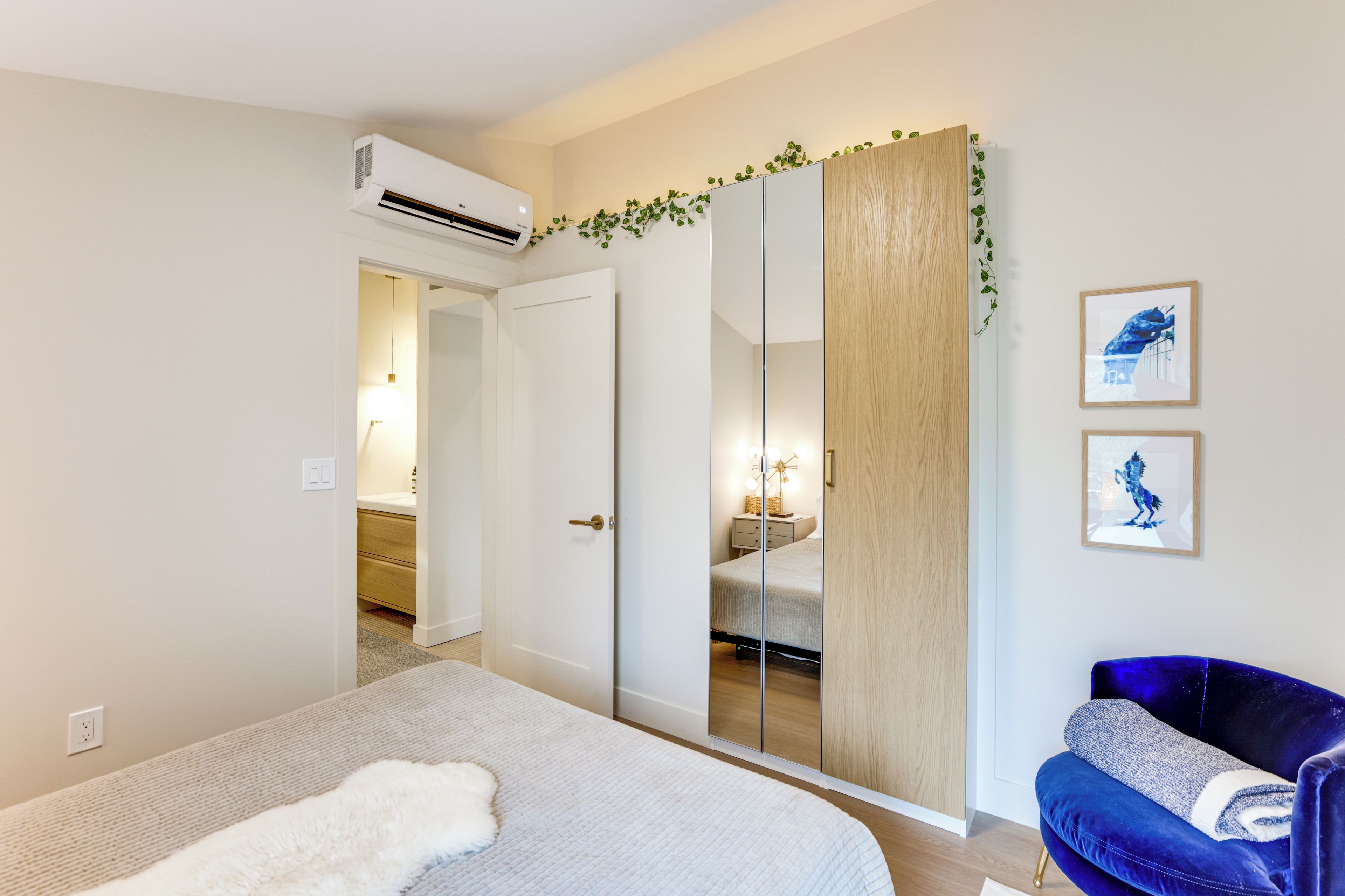 A bedroom with a bed, a wardrobe, a mirror, and a blue chair.