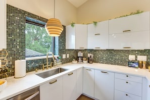 A modern kitchen with a large window, white cabinets, and a hanging pendant light. - Sip, Dine & Explore: Central Denver Escape! (Denver)