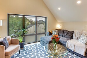 A modern living room with a large window, a sofa, a coffee table, and a potted plant. - Sip, Dine & Explore: Central Denver Escape! (Denver)