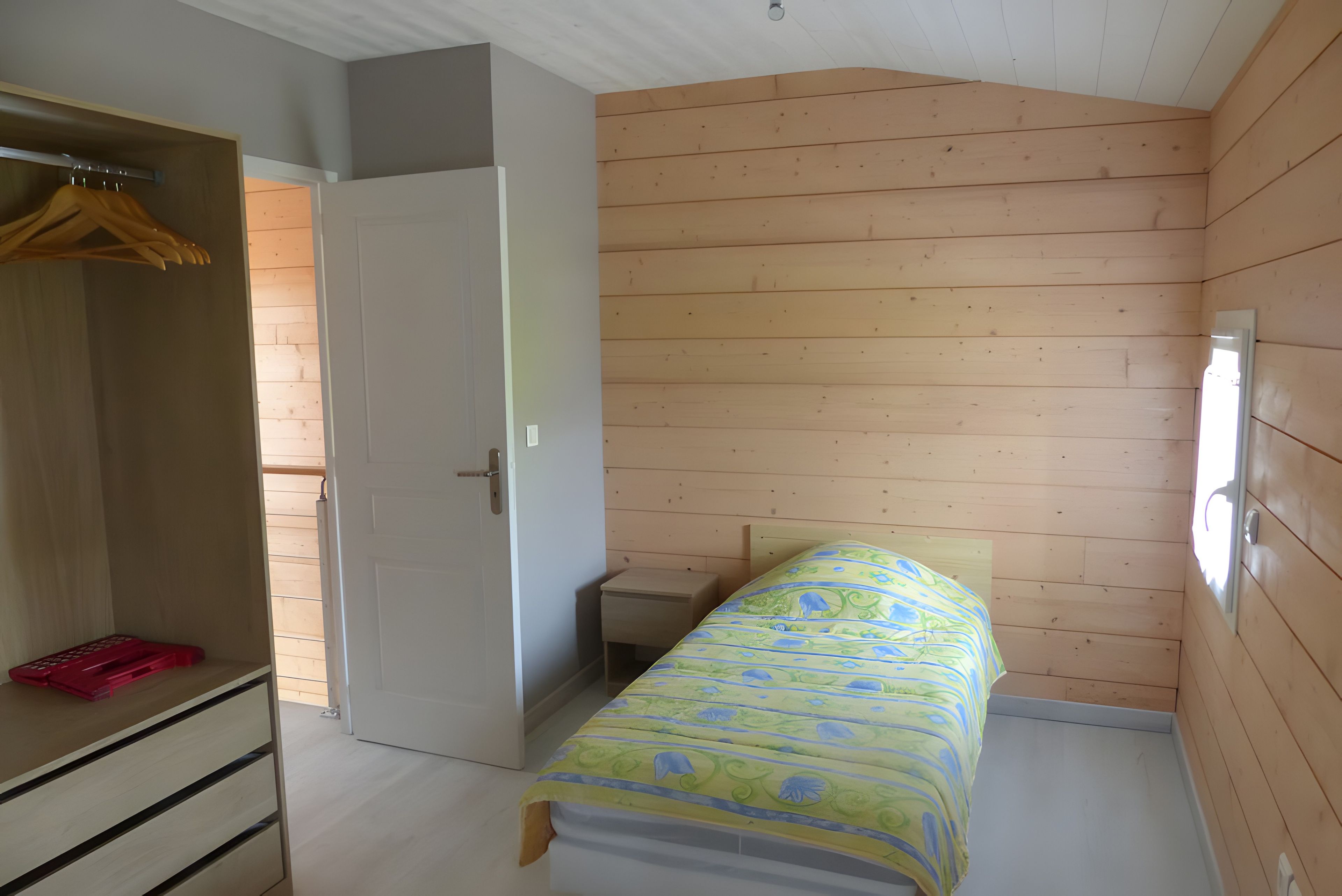 Een slaapkamer met een bed, een kledingkast en een klein nachtkastje.