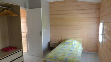 Een slaapkamer met een bed, een kledingkast en een klein nachtkastje.