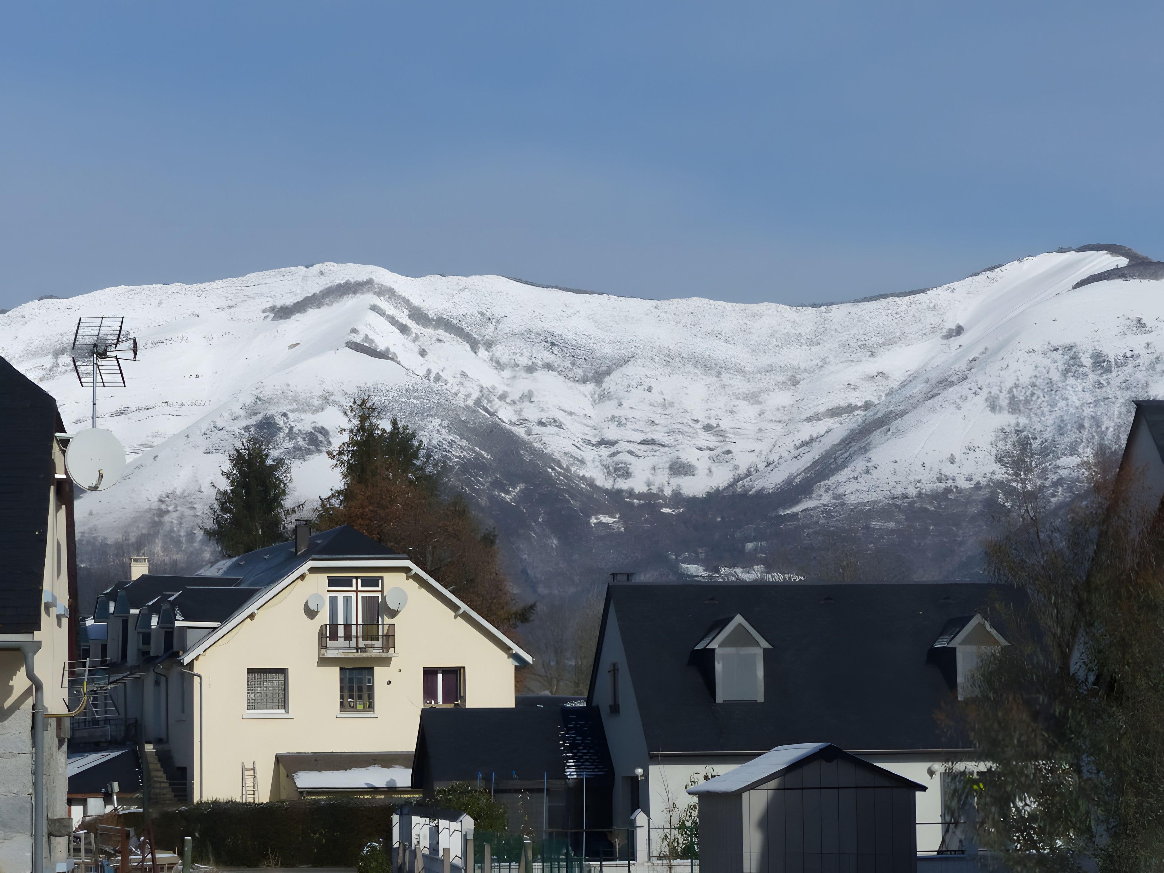 Ein Wohngebiet mit Häusern vor einem schneebedeckten Berg.