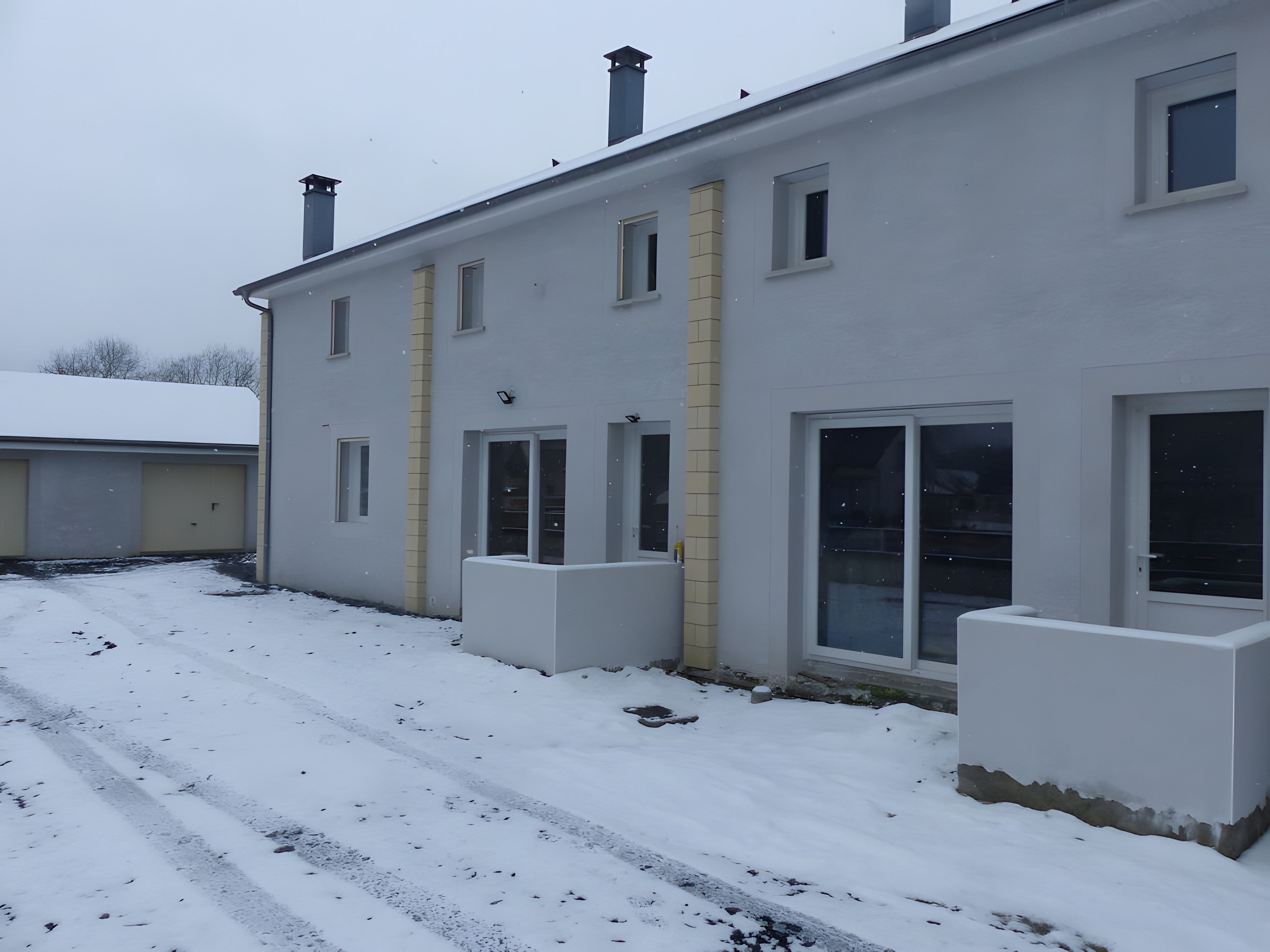 Een gebouw met twee verdiepingen, een plat dak en een met sneeuw bedekte grond.