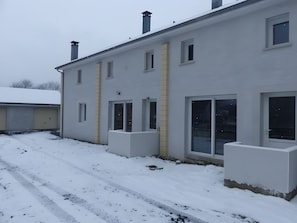 Een gebouw met twee verdiepingen, een plat dak en een met sneeuw bedekte grond.