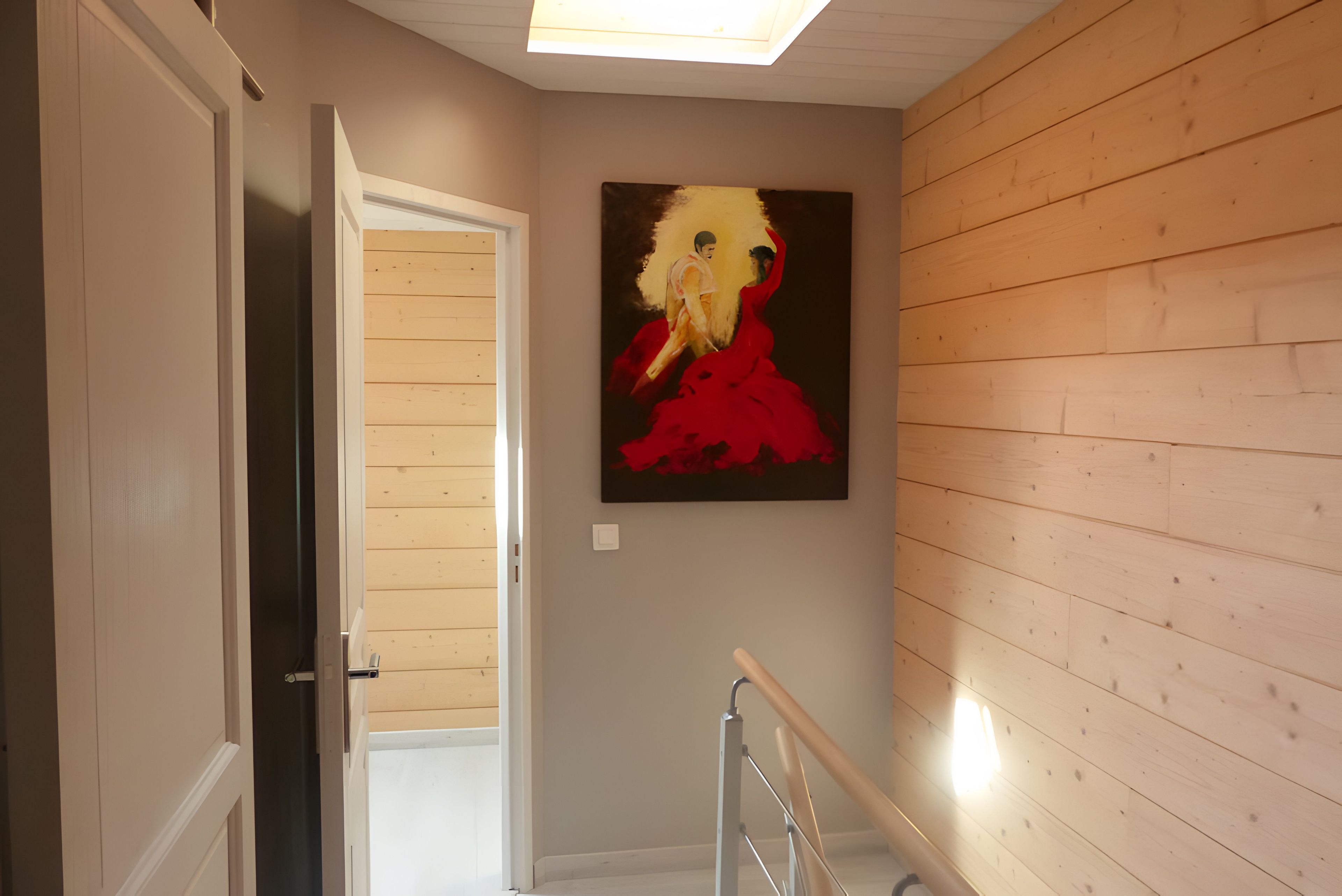 Een gang met een houten wand en een schilderij van een vrouw in een rode jurk.