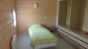 A small, single-bed room with wooden walls and a simple bed.