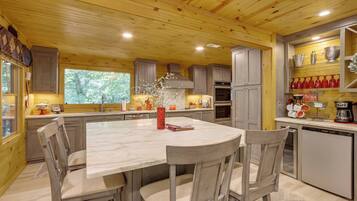 A modern kitchen with wooden ceiling, marble countertop, and built-in appliances.