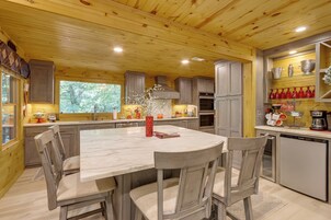 A modern kitchen with wooden ceiling, marble countertop, and built-in appliances.