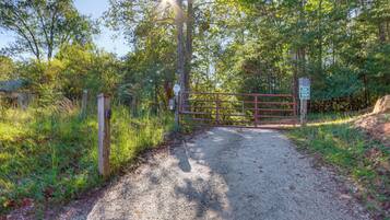 A gravel path leading to a gated entrance surrounded by trees.