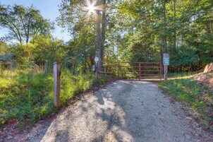 A gravel path leading to a gated entrance surrounded by trees.