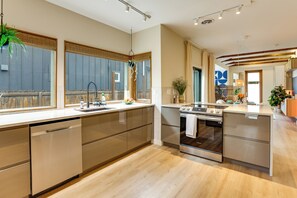 Een moderne keuken met roestvrijstalen apparatuur, een houten vloer en grote ramen.