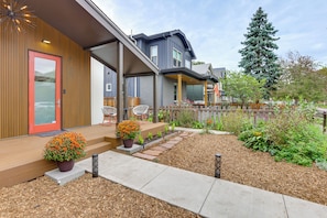 A residential property with a covered porch, outdoor seating, and a garden area with mulch and plants. - Walk to Rino & Coors Field! Modern Denver Home (Denver)