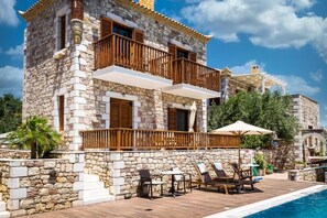 Ein Steinhaus mit Pool, Sitzgelegenheiten im Freien und einem Holzbalkon.