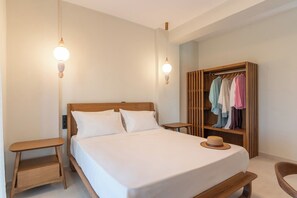 Ein ordentlich eingerichtetes Schlafzimmer mit einem Bett, Nachttischen, einem Kleiderschrank und aufgehängter Kleidung.