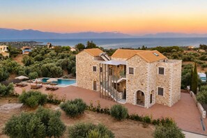 A stone villa with a swimming pool, surrounded by greenery and overlooking a coastal landscape. - Liokrina Suite 03 - Livadakia Poolside Getaway! (Livadakia)
