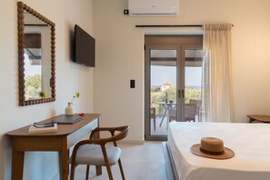 Ett hotellrum med ett skrivbord, en stol, en TV, en säng och utsikt genom dörren.