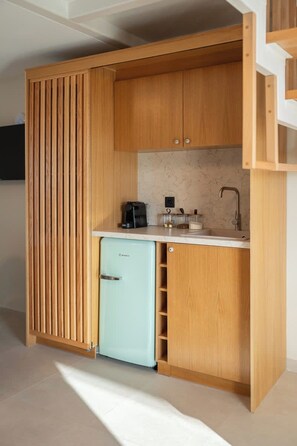 A compact kitchenette with a built-in refrigerator, a sink, and a coffee maker. - Liokrina Suite 05 - Livadakia Poolside Getaway! (Livadakia)
