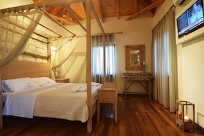 A bedroom with a four-poster bed, a wooden desk, a mirror, and a television. - Liokrina Villa Hellios - Livadakia Poolside Gem (Λιβαδάκια)