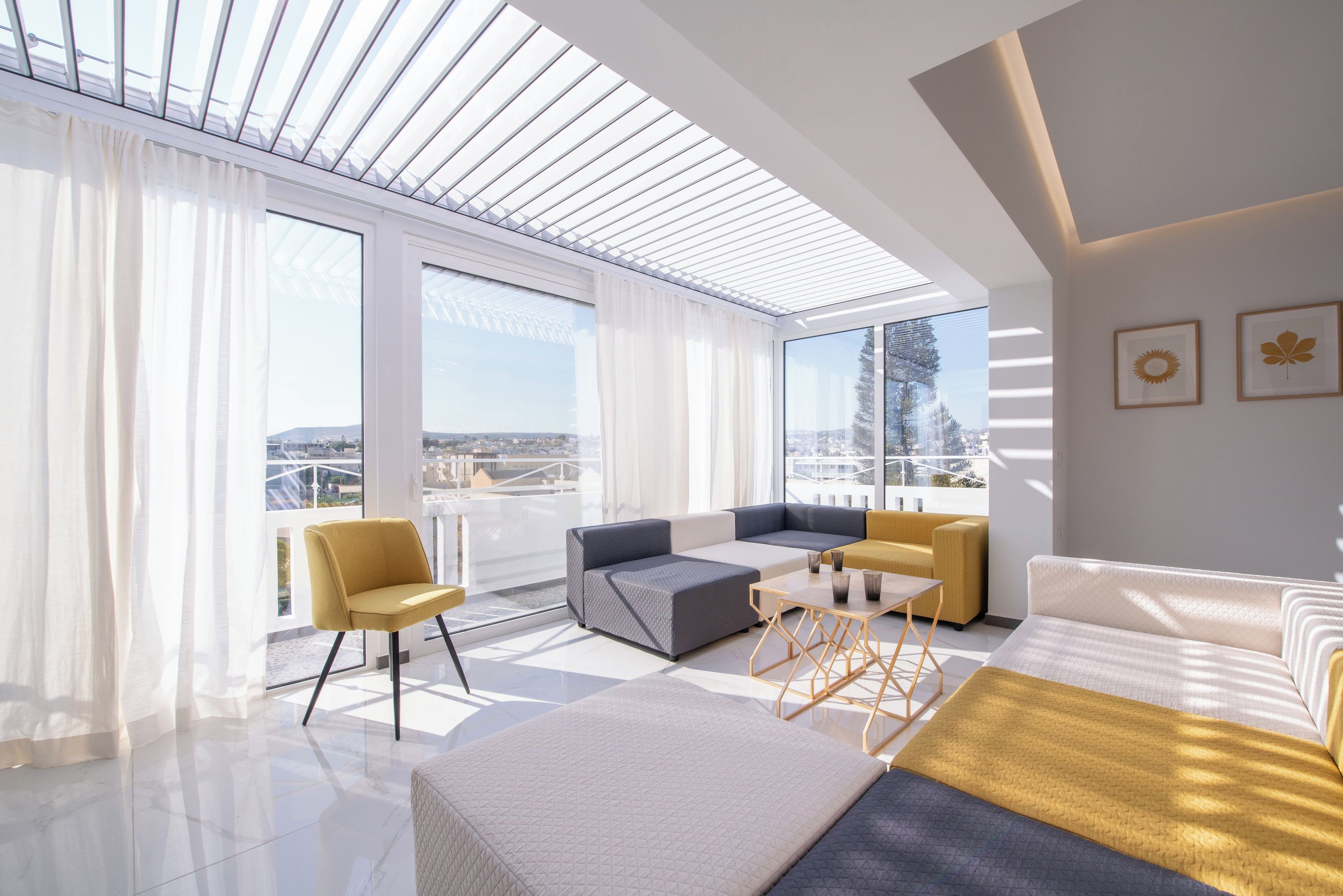 Una sala de estar moderna con un ventanal grande, un conjunto de sofás, una mesa de centro y vistas panorámicas de la ciudad.