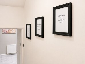A hallway with three framed quotes on the wall, a radiator, and a door leading to another room. - Access Great Venues, Airports, cLDN, Tottenham hale station apartment W/Parking! (London)