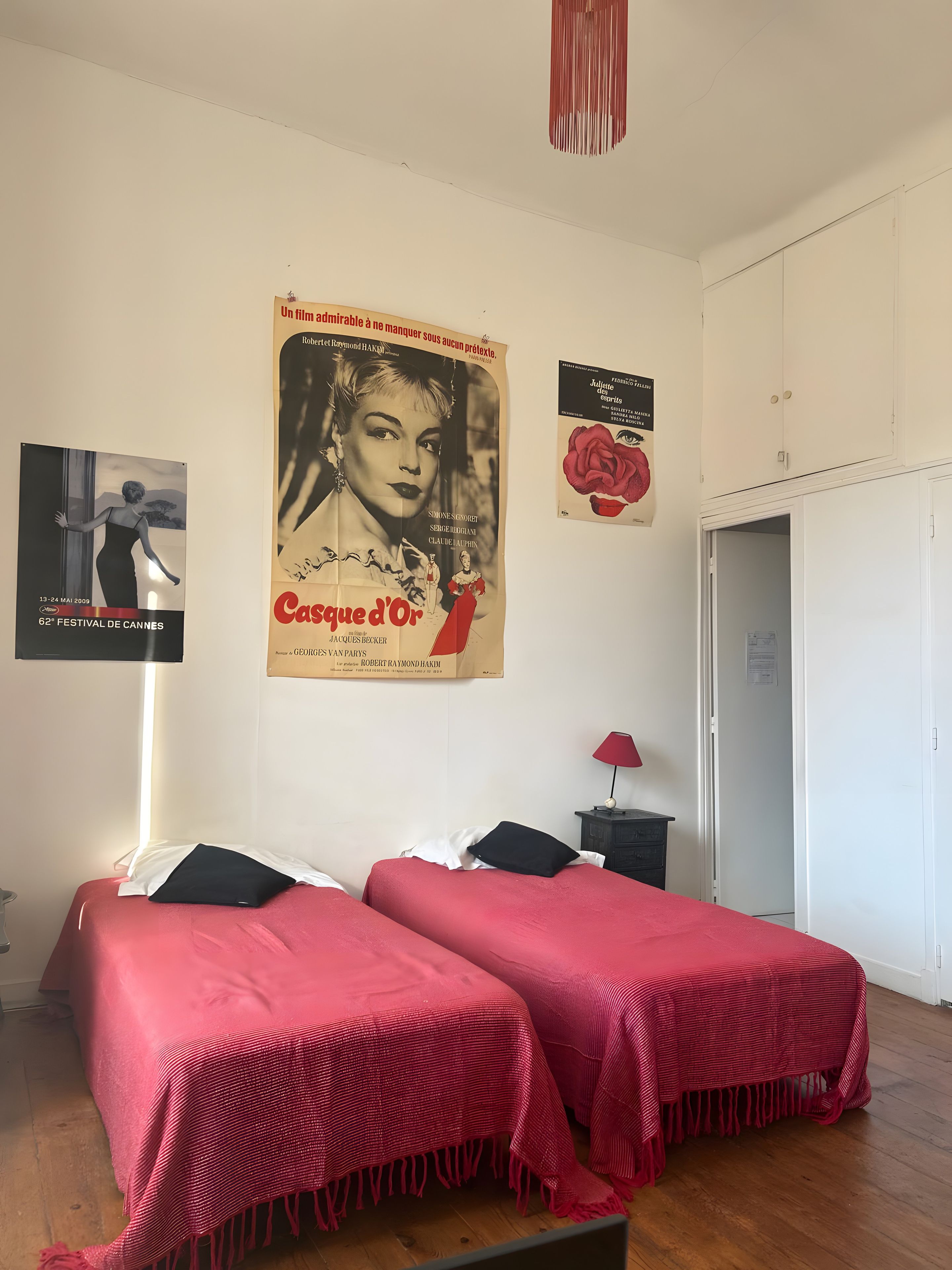 A bedroom with two beds, a wardrobe, and a poster on the wall.