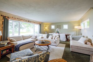 Ein Wohnzimmer mit einer Sofagarnitur, einem Couchtisch und einem Essbereich mit Tisch und Stühlen.