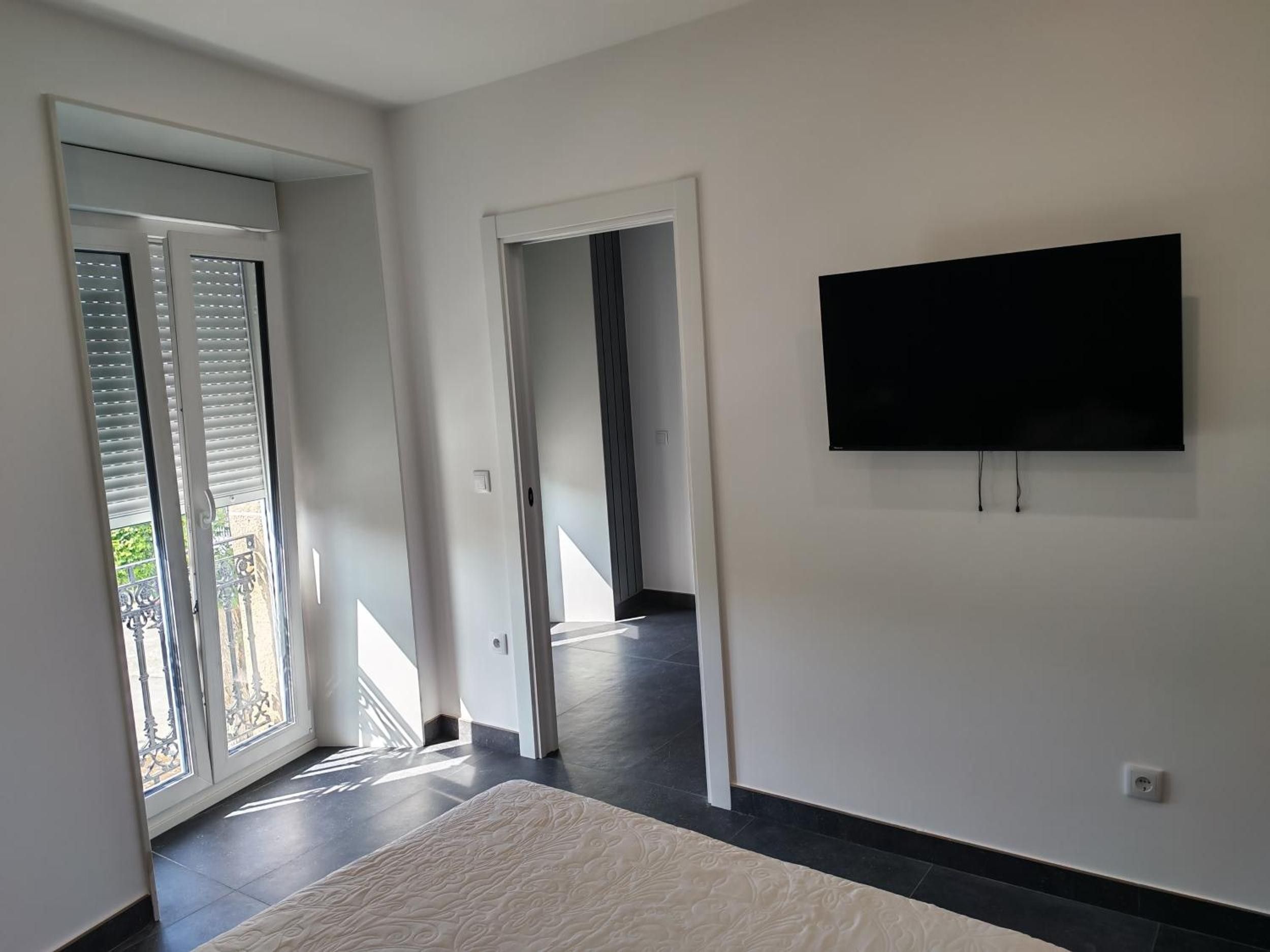 Ein modernes Interieur mit einem wandmontierten Flachbildfernseher, einer Schiebeglastür zu einem Außenbereich und einem gemusterten Teppichboden.