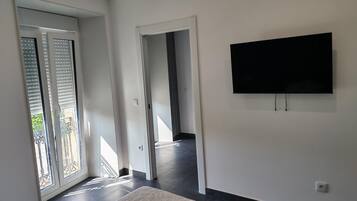Ein modernes Interieur mit einem wandmontierten Flachbildfernseher, einer Schiebeglastür zu einem Außenbereich und einem gemusterten Teppichboden.
