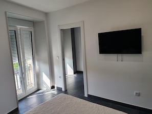 A modern interior with a flat-screen TV mounted on the wall, a sliding glass door leading to an outdoor area, and a patterned rug on the floor.