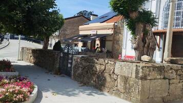 Un muro de piedra con una tapa de alcantarilla, un edificio con un letrero de casino, y un árbol en primer plano.