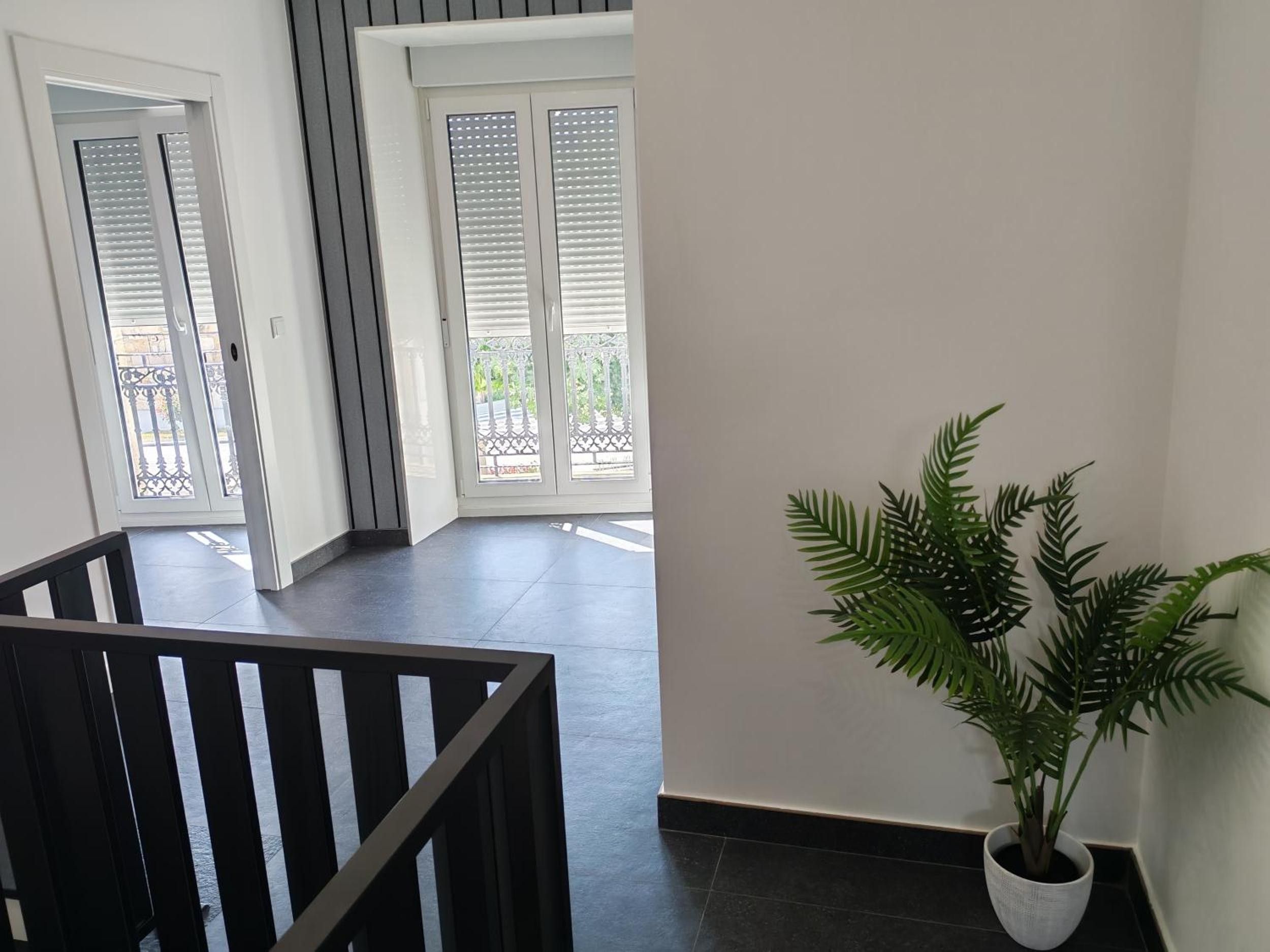 Ein modernes Interieur mit einer Treppe, einem Blumentopf und Blick auf den Balkon.