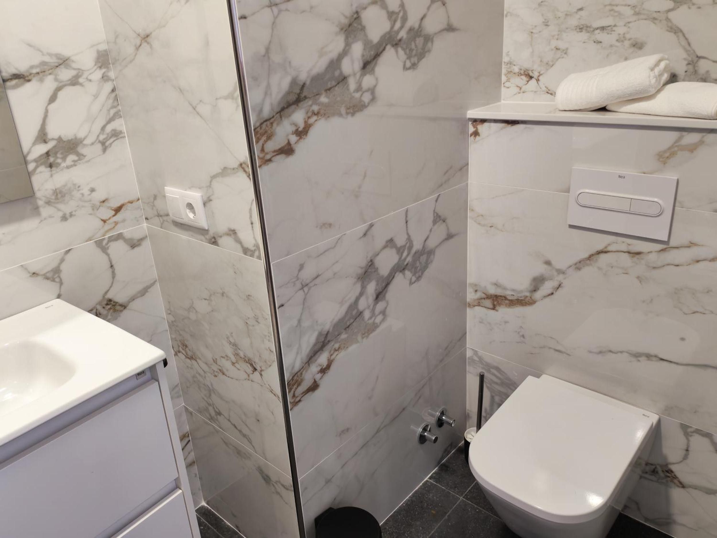 Un baño con un lavamanos blanco, un inodoro y un espejo.