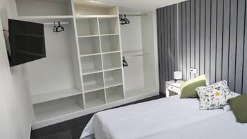 Un dormitorio con cama, armario, mesita de noche y televisor.