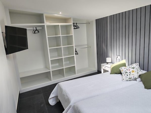 A bedroom with a bed, a wardrobe, a bedside table, and a television.