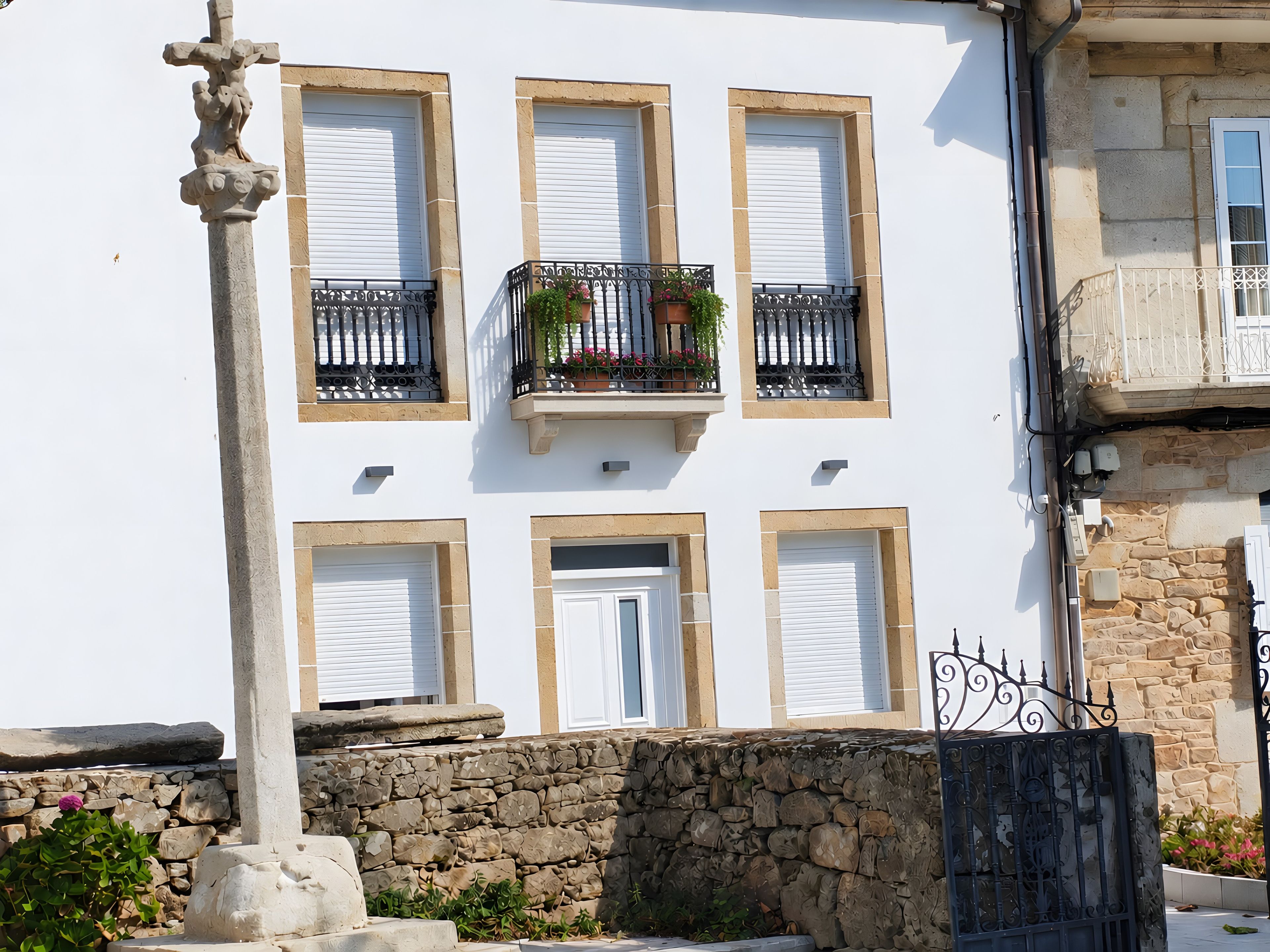 A building with six windows, a stone wall, and a metal gate.