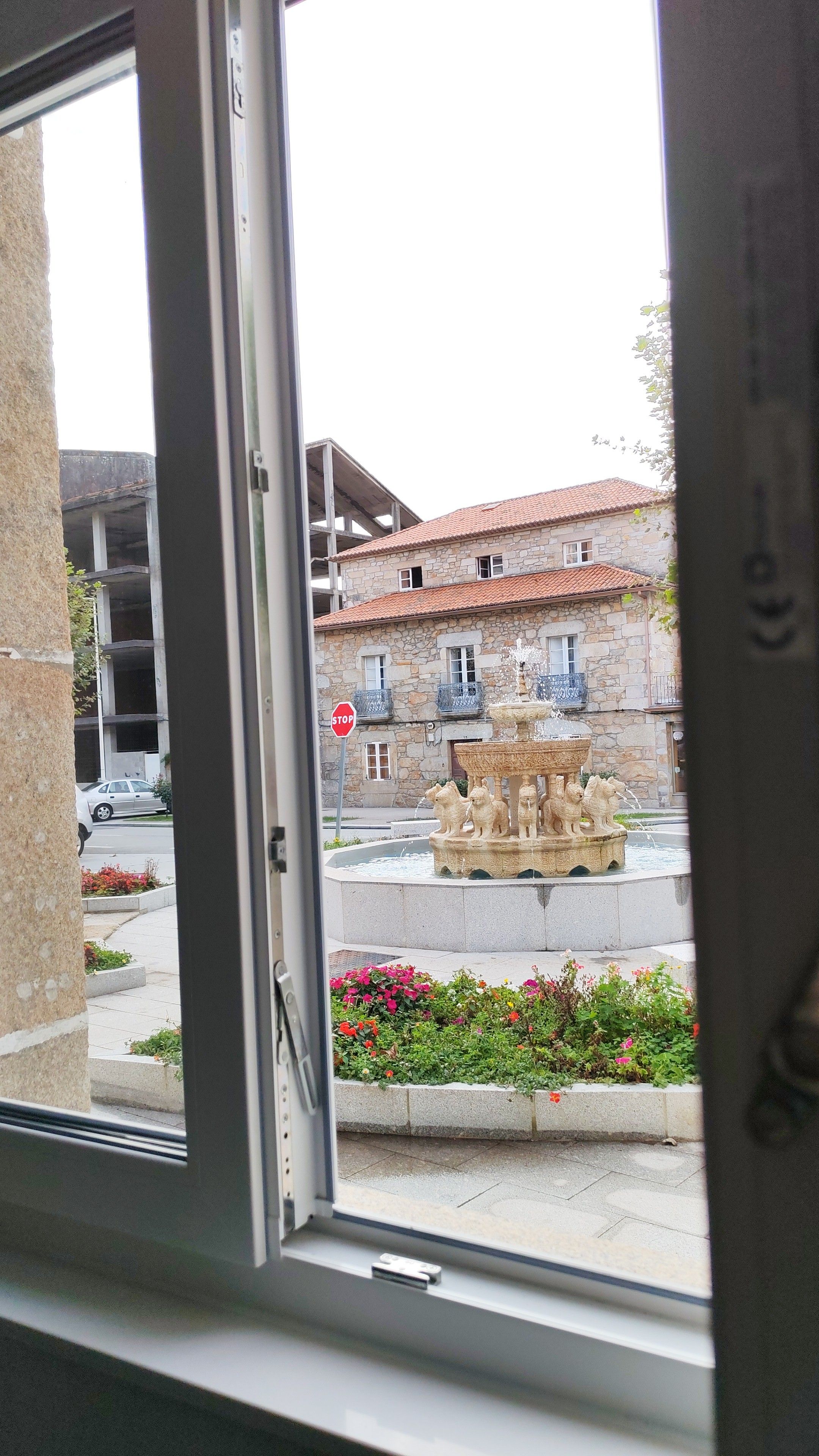 Un edificio de piedra con una fuente y una señal de parada al frente.