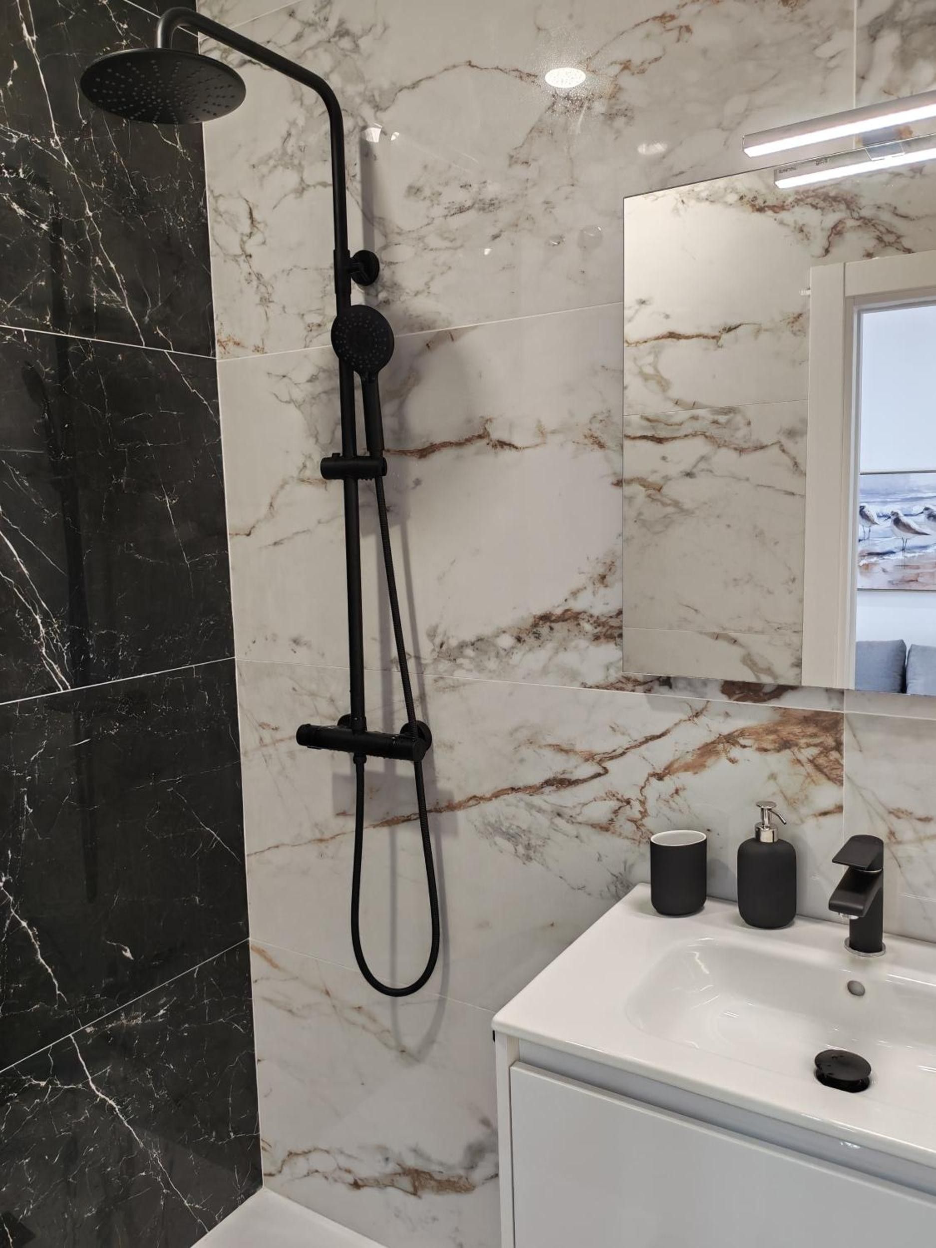 Ein Badezimmer mit Dusche, Waschbecken und Spiegel.