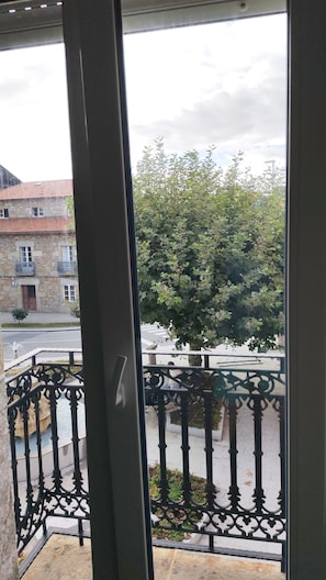 A view from a balcony with a stone building and a tree in the background.