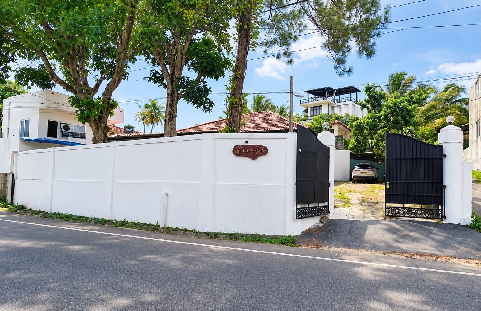 A gated property with a white wall, a sign reading 'Villa 73 Golf,' and a black gate.