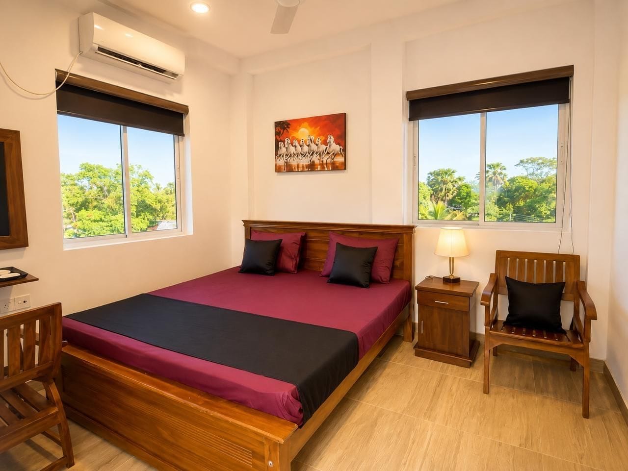 A bedroom with a bed, a desk, a chair, a nightstand, and a window with a view of greenery.