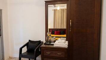 A wooden wardrobe with a mirror, a small black chair, and a tray with toiletries.