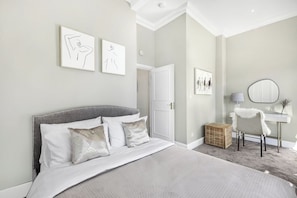 Ein Schlafzimmer mit Bett, Tür, Stuhl und Wandbildern.