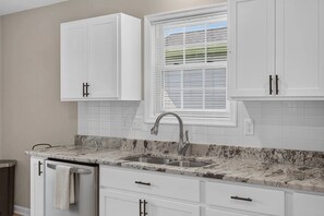 A kitchen with white cabinets, a granite countertop, a stainless steel sink, and a window with blinds. - Charming Mount Jackson Getaway (Mount Jackson)