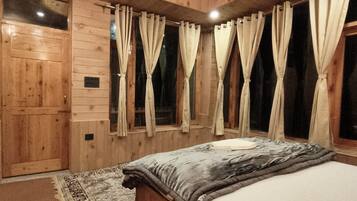 A wooden-paneled room with a bed, curtains, and a rug.