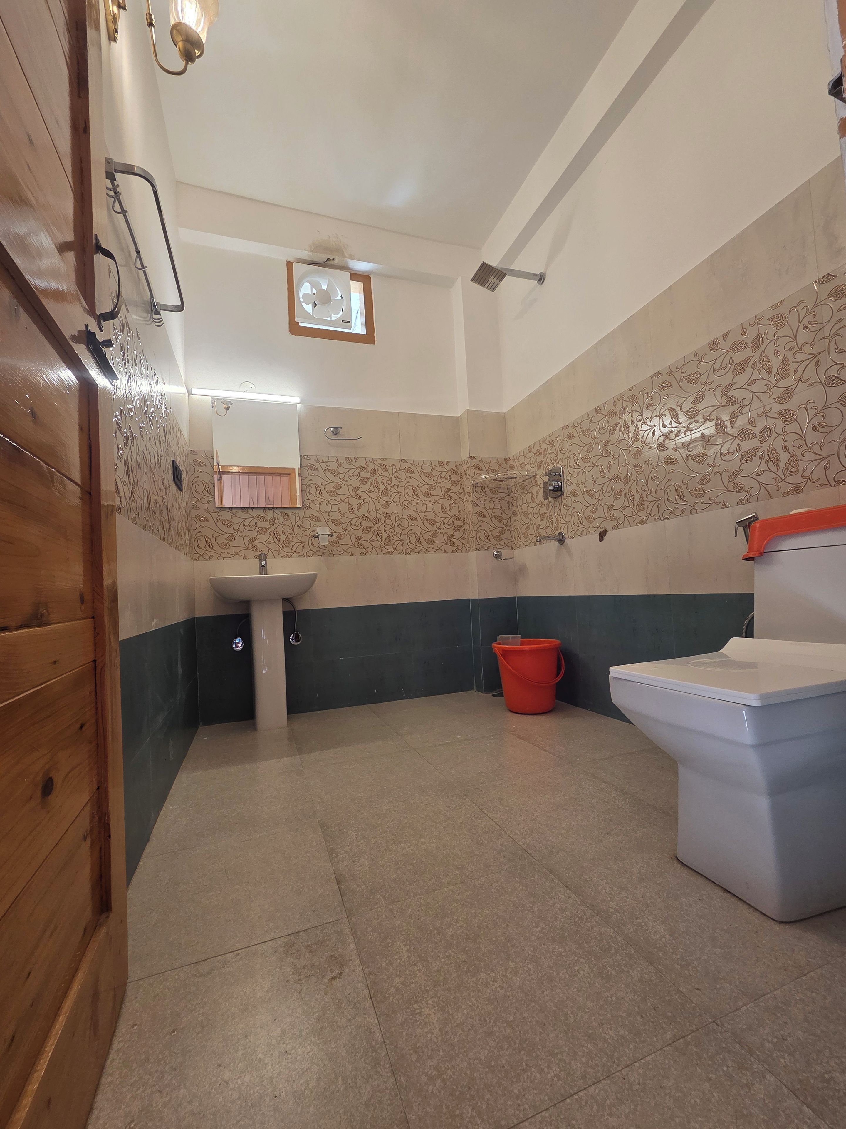 A bathroom with a sink, toilet, and a red bucket.