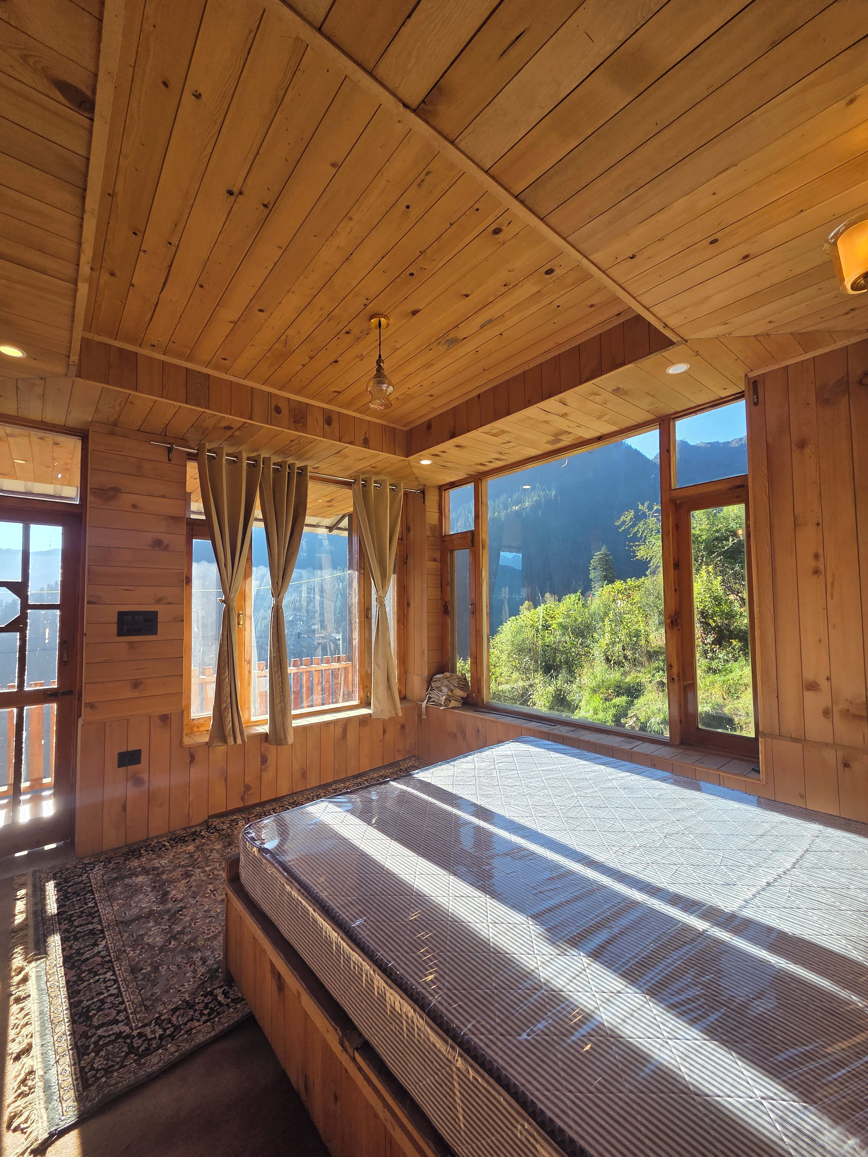 Quarto de cabana de madeira com uma cama grande, paredes de madeira e vista para as montanhas.